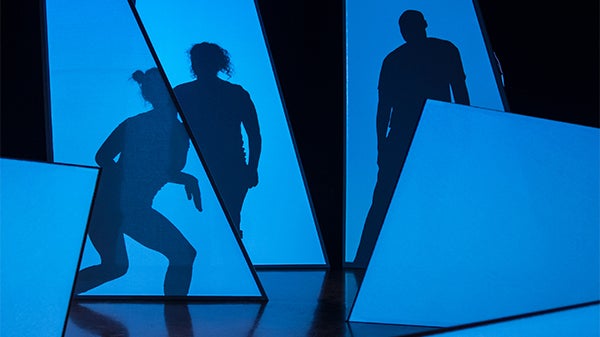 The shadows of three figures are projected on blue shapes