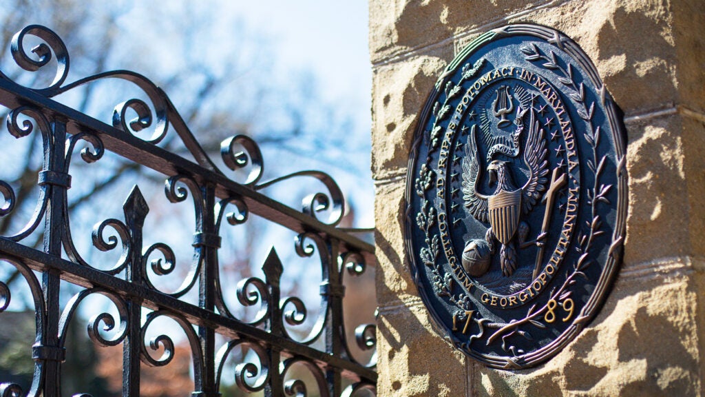 The front gate of Georgetown University campus with bronze logo affixed in stone